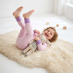 Child in pink pajamas with a plush toy on a fluffy rug