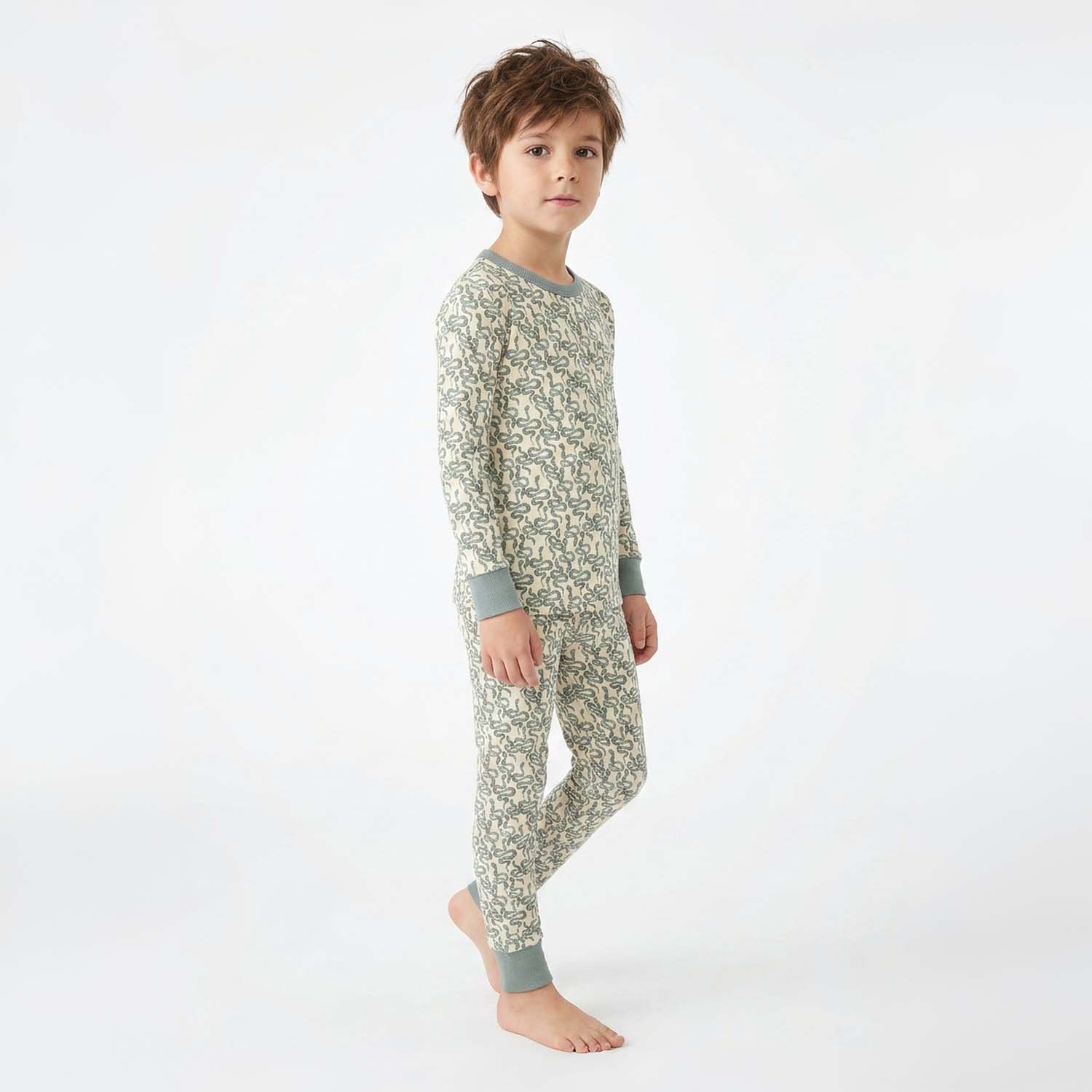 Child wearing a green snake patterned pajama set on a white background