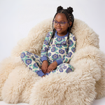 Young girl wearing a floral pajama set sitting on a fluffy chair.