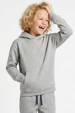 A smiling young child with curly blonde hair wearing a light heather gray pullover hoodie and matching gray sweatpants with navy drawstrings, posed against a clean white studio background.