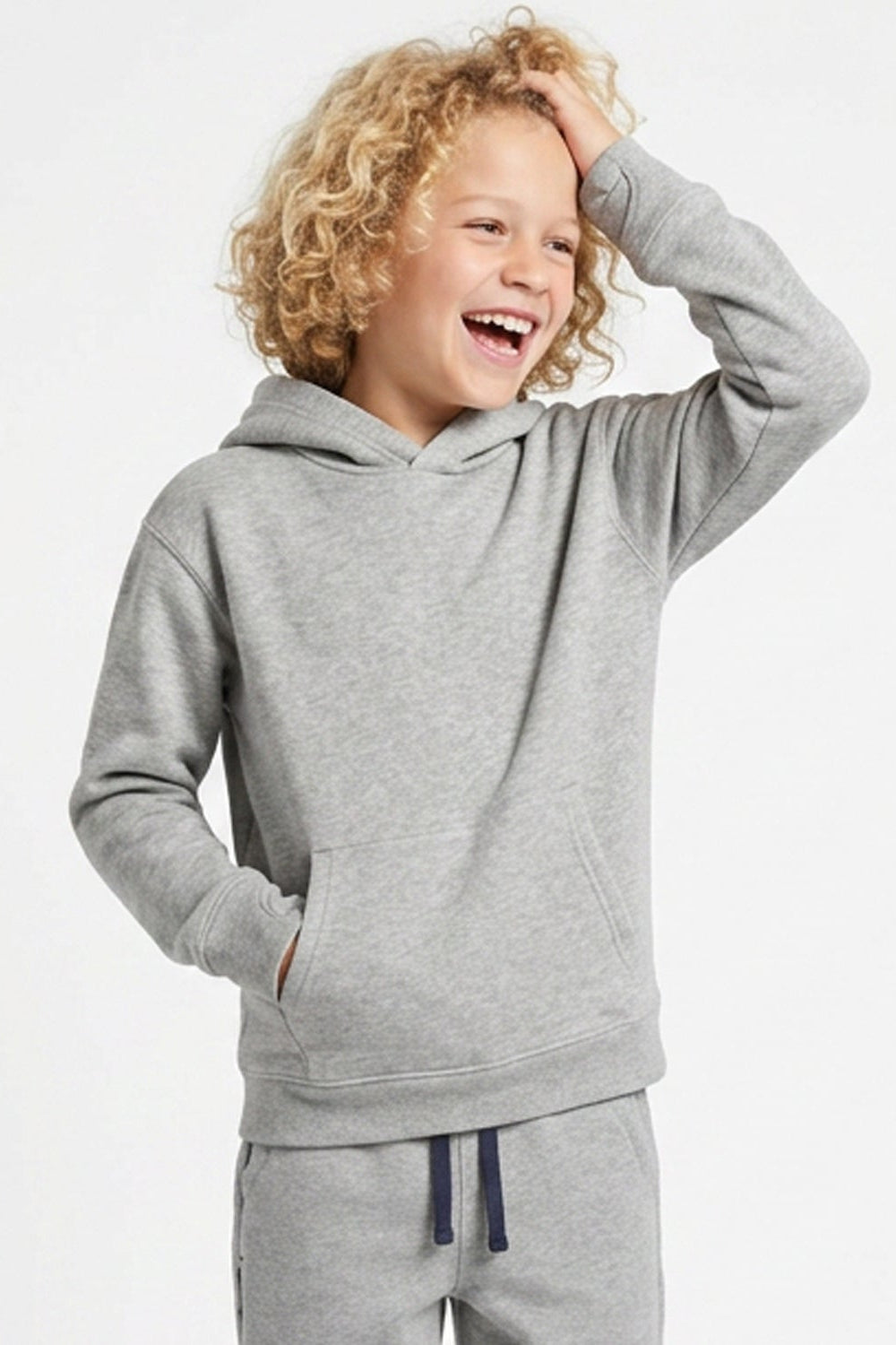 A smiling young child with curly blonde hair wearing a light heather gray pullover hoodie and matching gray sweatpants with navy drawstrings, posed against a clean white studio background.