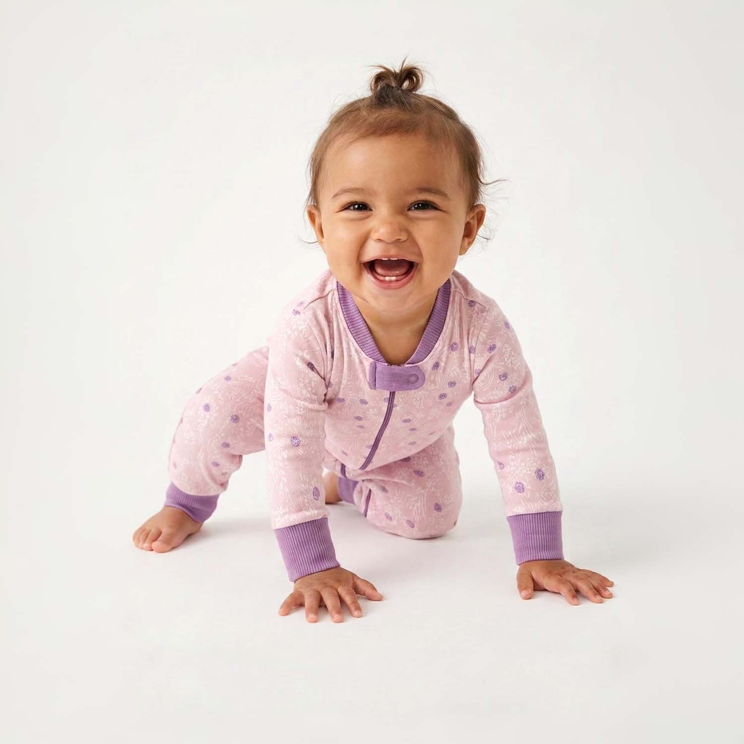 Baby in a pink and purple outfit with a white background