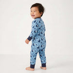 Baby standing wearing a blue pajama with animal pattern on a white background