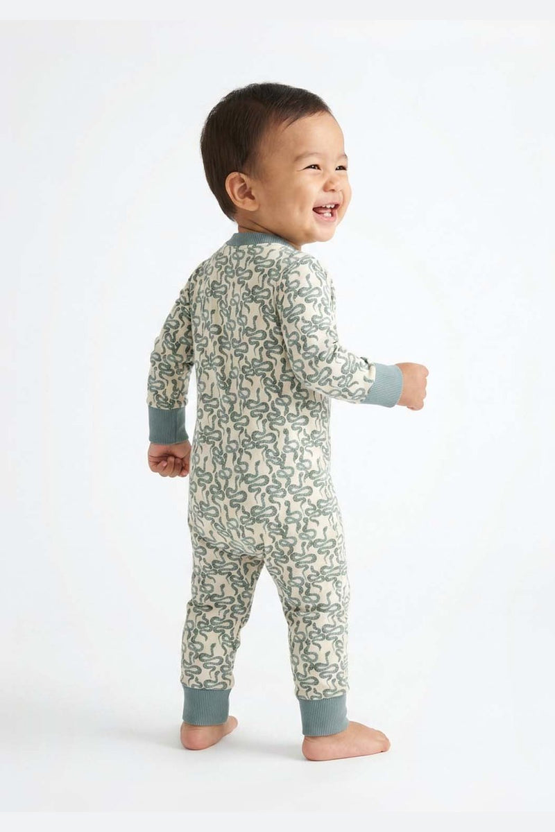 Child wearing a snake print onesie on a white background #cozy-coils