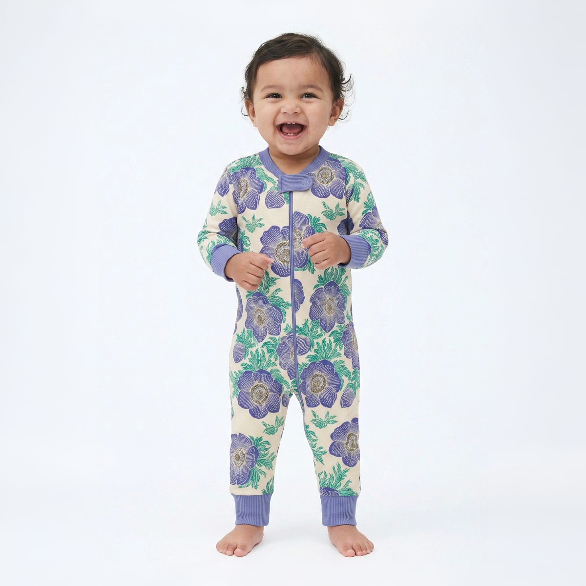 Baby wearing a floral patterned onesie with purple flowers on a white background