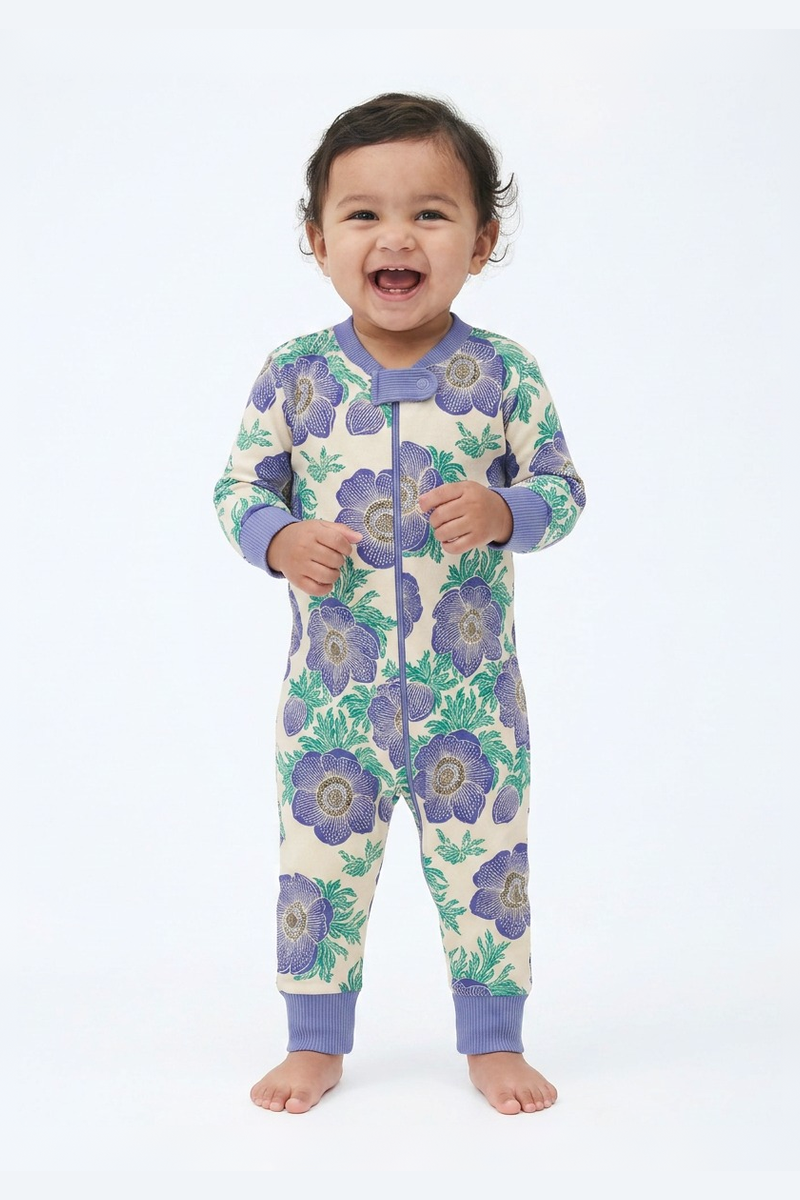 Baby wearing a floral patterned onesie with purple flowers on a white background