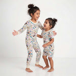 Two children wearing matching floral pajamas on a white background