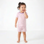 Child wearing pink pajamas with a white background