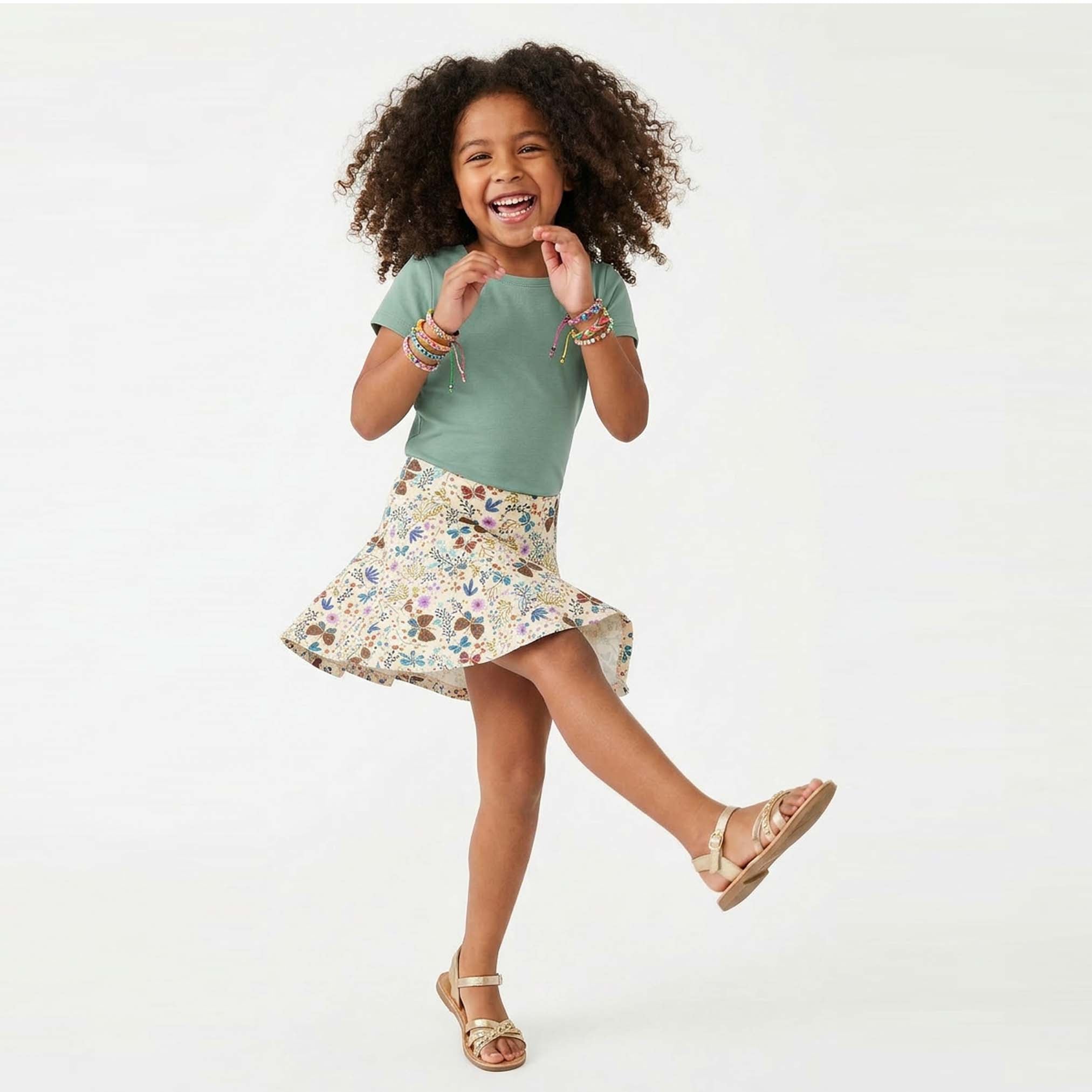 Young girl in a green shirt and floral skirt on a white background