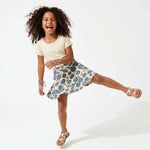 Child wearing a floral skirt and ivory top on a white background