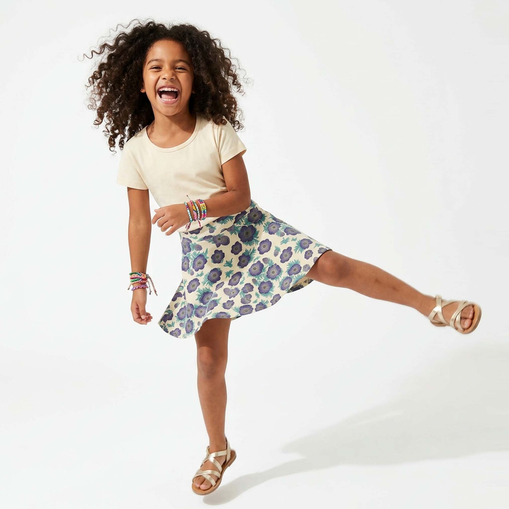 Child wearing a floral skirt and ivory top on a white background