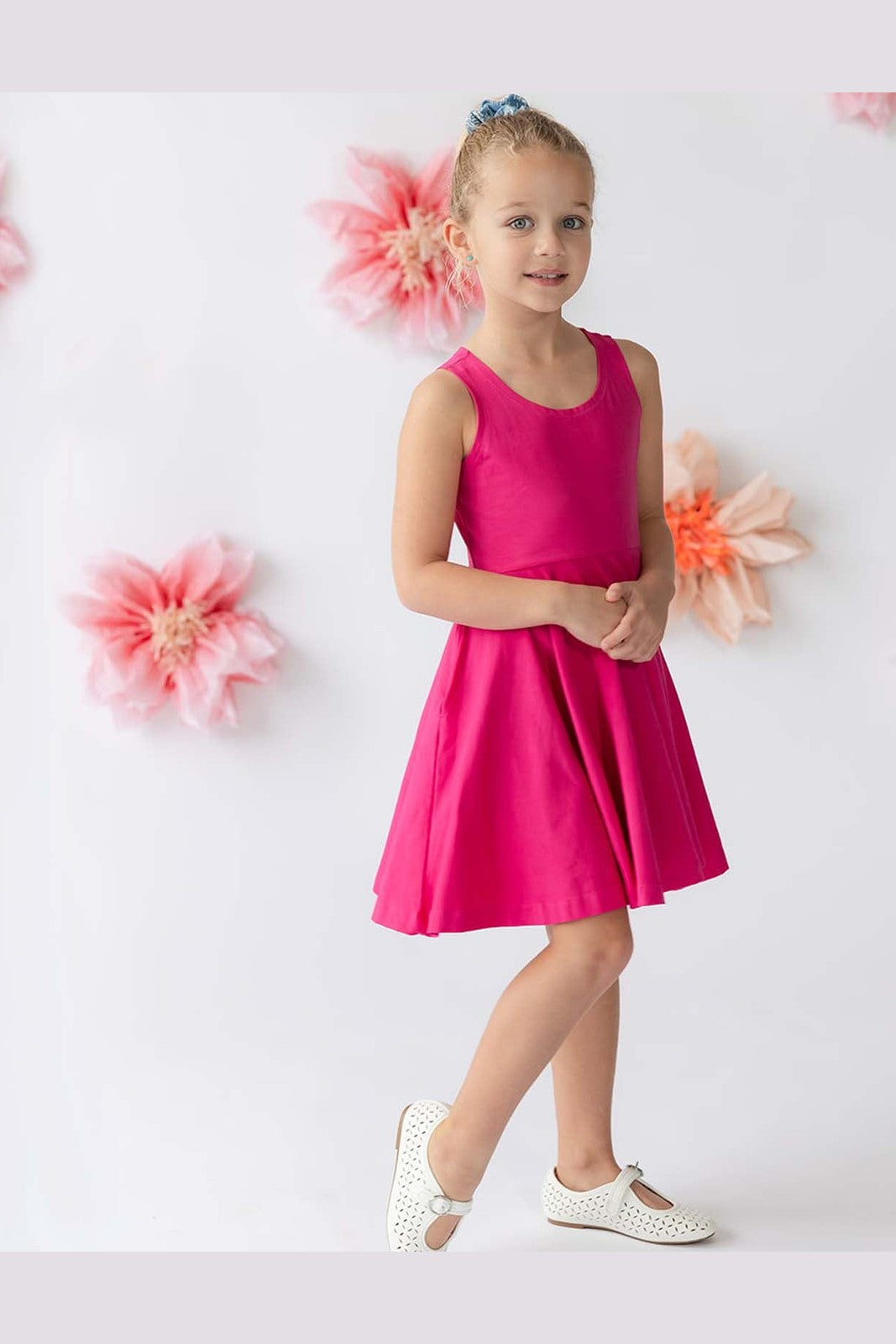 A girl wearing a bright pink dress against a floral background