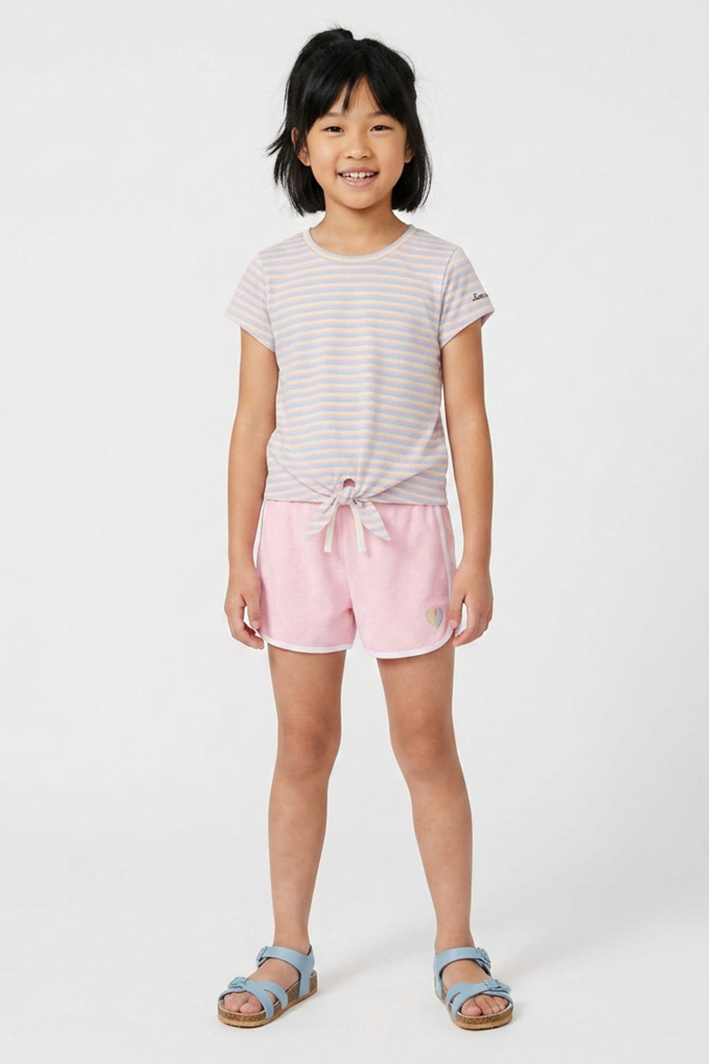 Young girl wearing a striped shirt and pink shorts on a white background