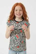 Young girl wearing a leopard print shirt with flower patterns on a white background