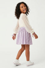 Young girl wearing a white blouse and purple skirt on a white background