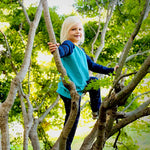 a young child climbing a tree wearing a navy and teal long sleeve baseball tee