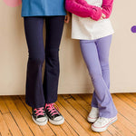 close of two kids wearing flared yoga pants. One pair is navy blue and one is light purple