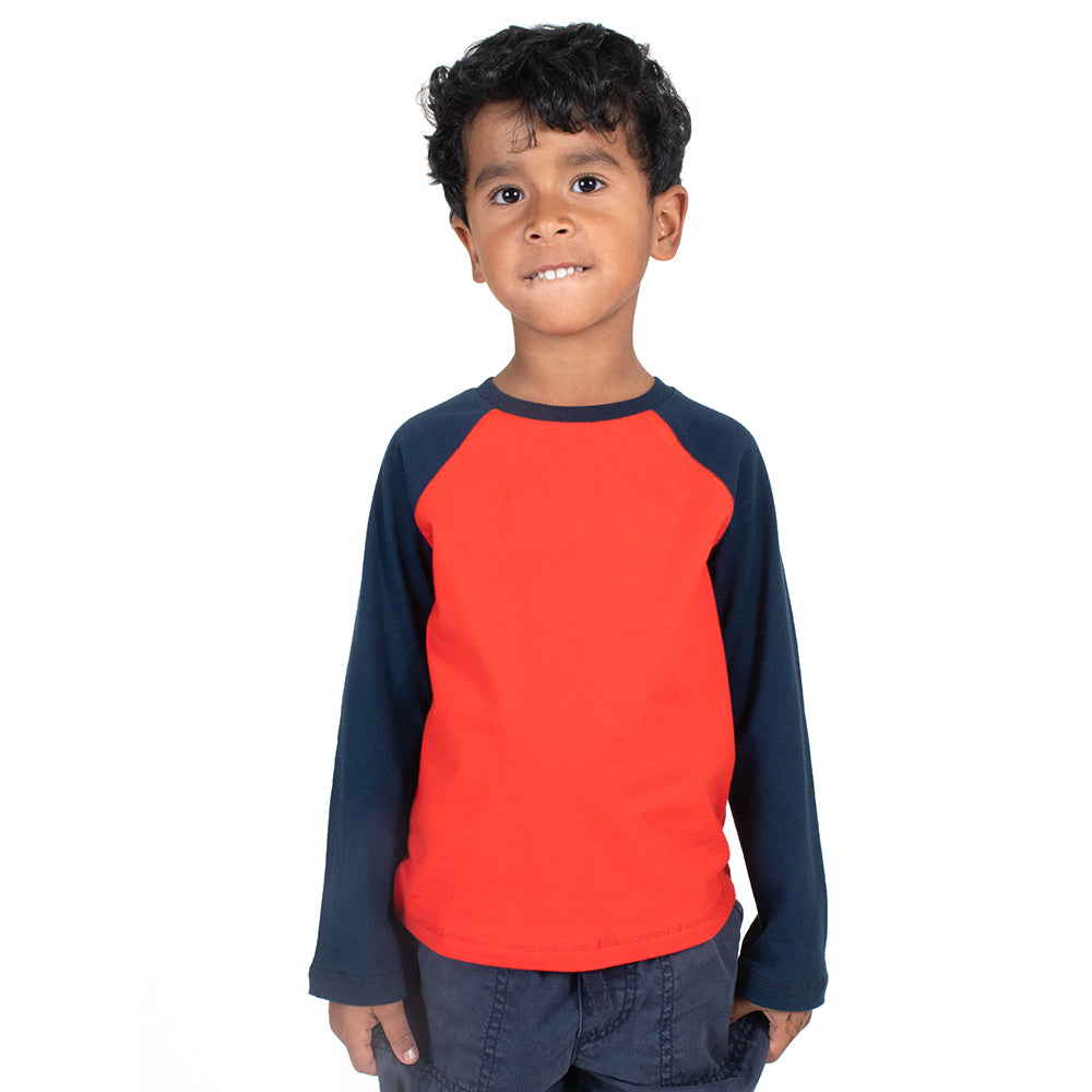 Young boy wearing a navy and red long sleeve tee shirt with a white background